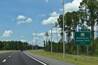 SR 23 arcs northward by Rattlesnake Bend to a six-ramp parclo interchange (Exit 31) with SR 21 (Blanding Boulevard).