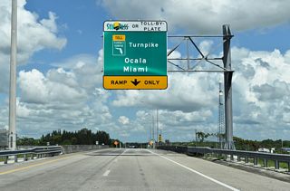 A lane drop occurs along SR 60 westbound at the signalized intersection with the Turnpike access road.