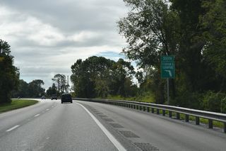 The original Wildwood main line toll plaza was located just beyond a brief roadway separation east of U.S. 301. Toll collection here ceased on July 7, 1995, with subsequent demolition of the booths completed as part of a $42 million modernization project to switch the northern Turnpike from ticket-based to coin-based toll collection.1