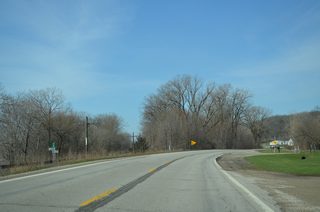 Milepost 76 stands ahead of the intersection with Geneva Hills Road on Iowa 22 west. The state highway diverges from the parallel DME Railroad to hug the bluff line over the succeeding stretch.