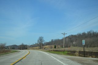 Great River Road trailblazer posted at Wildcat Den Road. Wildcat Den Road heads northwest to Wild Cat Den State Park.