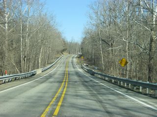 A view of SR 101 to the north of Arthur Curry Road passing through some woods.