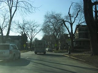 West of Broadway Street, Washington Boulevard becomes a residential two-way street even as it remains heavy with traffic. Since Interstate 69 was routed to the west of Fort Wayne, streets such as Washington and Jefferson Boulevards still carry heavy commuter traffic out of Downtown each weekday. In the second picture, Washington Boulevard crosses the intersection with College Street.