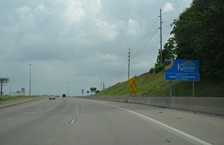A welcome to Kansas sign appears as I-670 turns south along a ridge line above adjacent Interstate 70.
