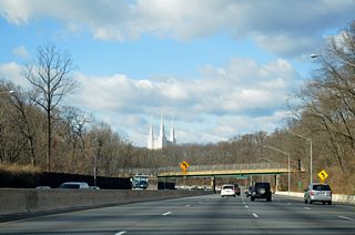 The Mormon Temple at Bethesda rises along the western horizon as Interstate 495 meanders around Rock Creek Park. Seminary Road (former MD 391), the MARC Brunswick Line, and Linden Lane pass over the beltway in the foreground. MD 391 was decommissioned along Seminary Road in 1999.