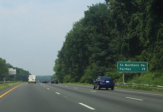 Older button copy distance sign referencing the mileage to Fairfax and Northern Virginia. Interstate 495 crosses the state line in five miles and reaches Interstate 66 in 11.5 miles.