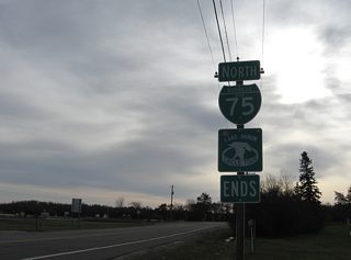 An end shield lies along Riverside Drive at the Sugar Island ferry dock entrance. Riverside Drive continues southward parallel to the Saint Mary River to McCarron and East 22 Mile Road east of Stirlingville and west of Munuscong Lake.