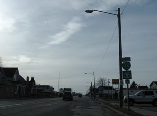 An assortment of businesses mix with residences along Ashmun Street south as drivers pass this reassurance marker at 8th Avenue.