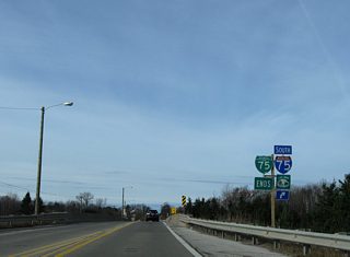 An end shield assembly precedes the I-75 underpass along Business Spur I-75 (Three Mile Road) west. Three Mile Road extends another 1.2 miles west along the city line to a dead end beyond 20th Street.