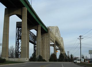 Ridge Street crosses West Portage Avenue next to pier supports for the International Bridge. A cantilevered steel through arch bridge, the International Bridge carries two lanes with a 27.9 foot deck and a length of 9,280 feet3