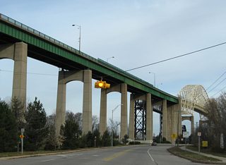 A flasher hangs above the intersection with Spruce Street just north of the West Portage Avenue Bridge. Spruce Street parallels Portage Avenue eastward to Business Spur I-75 (Ashmun Street) and Easterday Avenue.