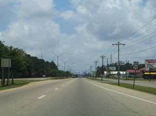 Continuing southwest from the exchange with MS 63/611 (Industrial Road), U.S. 90 (Denny Avenue) constitutes a four lane commercial arterial with a north side service road.