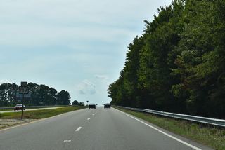 Curving west, U.S. 70 spans a Norfolk Southern Railroad line ahead of U.S. 70A west to Pine Level.