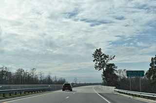 The Wilmington Bypass curves southwest onto a long viaduct spanning marshland ahead of the Cape Fear River.