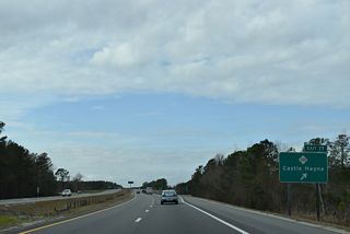 Westbound at the folded diamond interchange (Exit 18) with NC 133. NC 133 (Castle Hayne Road) heads north 2.42 miles through Skippers Corner to combine with U.S. 117 at Castle Hayne.
