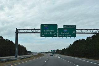 A collector distributor roadway separates from the NC 140 mainline for Exit 20B to Raleigh and Exit 20A to Wilmington.