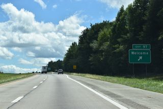 Old US Highway 52 continues southwest from the folded diamond interchange at Exit 97 into the community of Welcome.