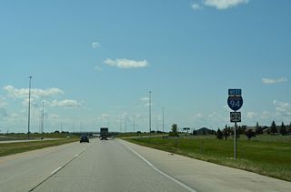 A second set of shields for I-94/U.S. 52 west posted between Exits 348 and 347. Apartments and duplexes abut the north side of the freeway here.