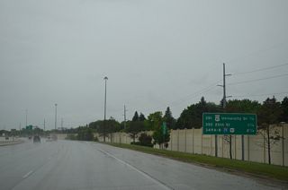 Interchange sequence signs are typically placed between every exit within the Fargo area on I-29 and I-94. This panel precedes the six-ramp parclo interchange at Exit 351. U.S. 81 Business follows University Drive northward from 52nd Avenue S at Maple Valley to 13th Avenue S at the Roosevelt/NDSU neighborhood. Most of the route is a commercialized arterial.