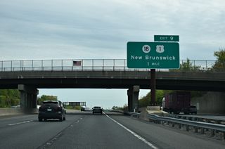Interstate 95 northbound at the Sullivan Way overpass, one mile south of the trumpet interchange (Exit 9) with Route 18. Route 18 meets U.S. 1 just west of I-95 at a cloverleaf interchange before transitioning onto Memorial Parkway along the Raritan River.