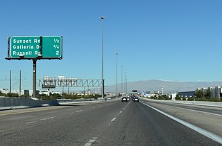 Several warehouses and auto dealerships line either side of I-11 (Oran K. Gragson Freeway) northward to Exit 64 A for Sunset Road.