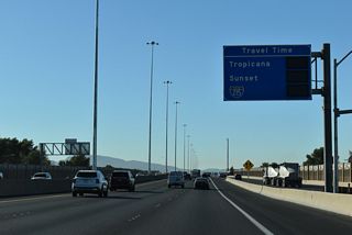 A travel time information board appears beyond the entrance ramp from Charleston Boulevard. Travel times vary throughout the day depending on the volume of traffic.