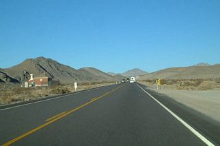 A switching house for telecommunications appears along the north side of U.S. 95 in the valley separating the Specter Range and Spring Mountains.