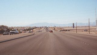 Prior to the completion of the Interstate 215 freeway, this view showed SR 146 west at Gibson Road. The beginning of the limited access freeway that becomes Interstate 215 was visible just beyond the Gibson Road traffic light.