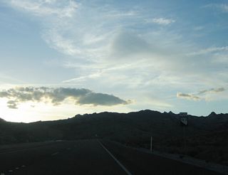 A Nevada 163 west reassurance shield is posted along the drive up the hill.