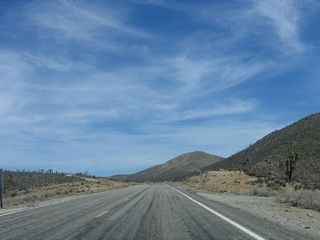 Continuing to gain elevation, Joshua trees start appearing along Nevada 164 (Joshua Tree Highway) east. Crescent Peak rises in the distance to the south of the highway.