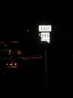 After the Interstate 15 interchange, this eastbound reassurance shield is posted next to the Excalibur resort prior to intersecting Las Vegas Boulevard (Former Nevada 604/U.S. 91-466). The MGM Grand resort and New York New York resort are visible in the background of this nighttime picture.