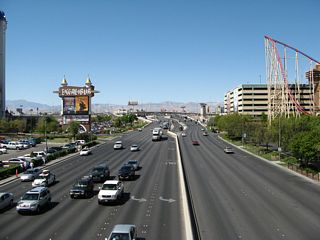 Twelve lanes of Tropicana Avenue provide for traffic between Las Vegas Boulevard and Interstate 15. This view is from the pedestrian bridge between Excalibur resort and the New York New York resort. Seven lanes travel east at this point, and five lanes travel west. Note the use of botts dots pavement lane markings.