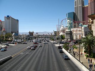 Seven lanes of westbound Tropicana Avenue approach the intersection with Las Vegas Boulevard. The New York New York resort dominates the view on the northwest corner of this major intersection. Turn left on Las Vegas Boulevard to the Excalibur, Luxor, and Mandalay Resorts. For most other resorts on the Strip, turn right (north) on Las Vegas Boulevard. This view is from the pedestrian bridge between MGM Grand resort and the Tropicana resort.