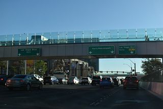 Tropicana Avenue proceeds east to Las Vegas Boulevard, an eight lane arterial running along the length of the Las Vegas Strip. Pedestrian overpasses span both urban boulevards on all sides of the busy intersection.