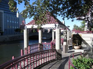 An elaborate network of decorative ramps, railings, and kiosks line the south side of the Truckee River through downtown Reno. The Virginia Street bridge is visible in the background. Along the south side of the river are several water features.