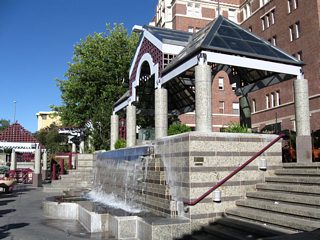 An elaborate network of decorative ramps, railings, and kiosks line the south side of the Truckee River through downtown Reno. The Virginia Street bridge is visible in the background. Along the south side of the river are several water features.