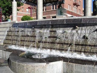 An elaborate network of decorative ramps, railings, and kiosks line the south side of the Truckee River through downtown Reno. The Virginia Street bridge is visible in the background. Along the south side of the river are several water features.