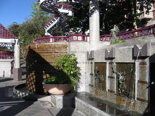 An elaborate network of decorative ramps, railings, and kiosks line the south side of the Truckee River through downtown Reno. The Virginia Street bridge is visible in the background. Along the south side of the river are several water features.