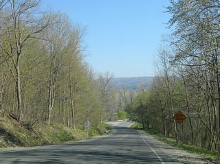 Approaching NY 436, CR 9 (Ossian Hill Road) intersects Eades Road. Representing the original alignment of NY 245, Eades Road ascends westward,