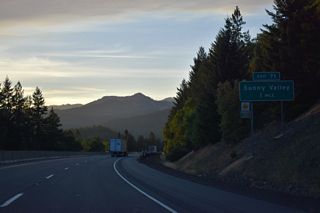 Interstate 5 lowers from Sexton Summit to Exit 71 with Lariet Drive west and Sunny Valley Loop east at Sunny Valley.
