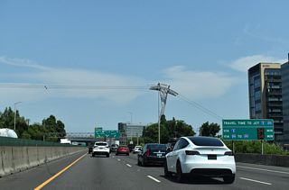 A support structure of the Portland Aerial Tram rises along the east side of Interstate 5 ahead of the separation with I-405 (S Harbor Drive). The tram connects Marquam Hill and Oregon Health and Sciences University (OHSU) with the South Waterfront neighborhood.