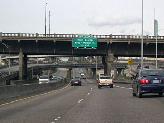 The advance sign for Exit 302 A for the Moda Center, a sports and entertainment venue, and the couplet of Broadway and Weidler Street appears at the Burnside Bridge.