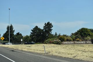 Exit 308 parts ways with I-5 north for Tomahawk Island Drive at Jantzen Beach. Commercial properties line both sides of Interstate 5 ahead of the Interstate Bridge leading into Vancouver, Washington.