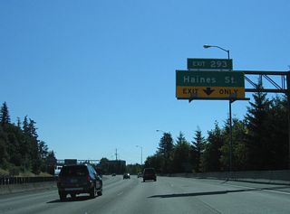 The on-ramp from OR 99W and SW 64th Avenue forms an auxiliary lane on I-5 south to the parclo interchange at Exit 293. Interstate 5 leaves the city of Portland and enters Washington County here.