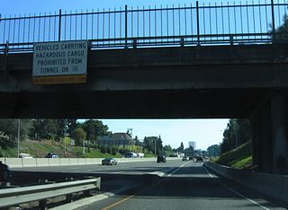 Truckers bound for U.S. 26 (Sunset Highway) west are advised of the hazardous materials prohibition through the East Vista Ridge Tunnel with this sign at the Skidmore Street overpass.