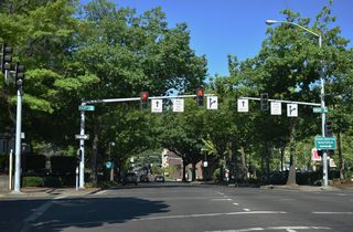 6th Avenue passes under the viaduct along Coburg Road west ahead of High Street. An off-ramp from Coburg Road south merges with 6th Avenue at the signalized intersection. High Street north leads the 5th Street Public Market and Skinner Butte Park along the Willamette River.