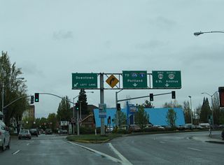 Broadway Street west where Mill Street turns north. Overheads here allude to Mill Street as part of OR 99 north and OR 126 Business west, but signage preceding Hilyard Street indicates that the two routes turn there.