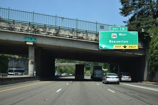 Passing under SW Park Avenue, an auxiliary lane briefly joins I-405 north as U.S. 26 enters from SW 6th Avenue. U.S. 26 west departs next for Sunset Highway, a freeway linking I-405 with the Oregon Zoo and World Forestry Center en route to Beaverton.