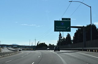 Previously a cloverleaf interchange, improvements to Exit 13 included removing two of the loop ramps and adding a flyover between I-5 north and OR 569 west. The freeway ends ahead at a traffic signal with the ramp from I-5 south.