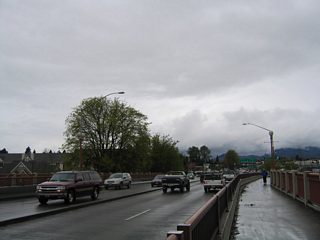The four lane truss bridge of Coburg Road passes over the northern banks of the Willamette River and Club Road ahead of the intersection with Martin Luther King Jr. Boulevard.